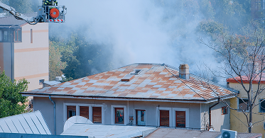 close-up-firefighters-platform-truck-helping-with-fire-from-burning-building-firemen-with-equipment-water-working-extinguish-flames-roof-house-city-landscape